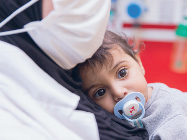 Mutter mit Maske und Baby im Caritas Baby Hospital