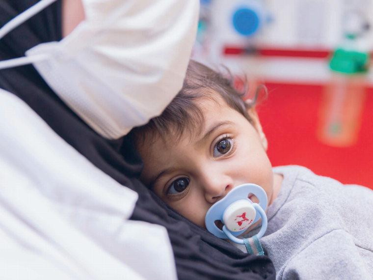 Mutter mit Maske und Baby im Caritas Baby Hospital